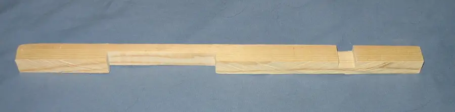 Wooden entrance reducer bar with two notches of different sizes cut into one edge, lying on a blue cloth